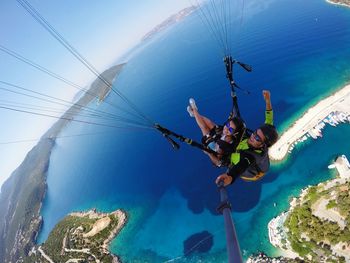 High angle view of couple paragliding over sea against sky