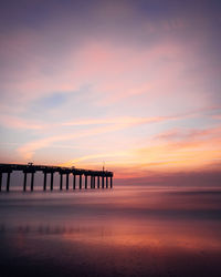 Pier over sea against sky during sunset