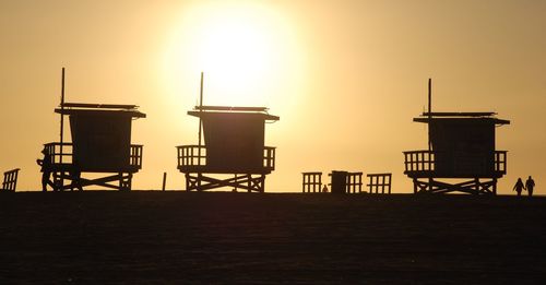 Silhouette lifeguard hut against sky during sunset