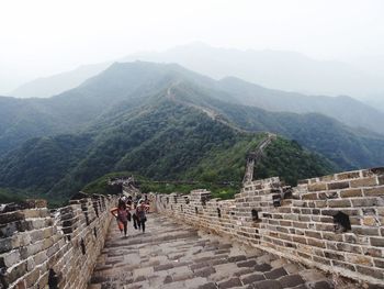 Tourists on top of historic building against sky