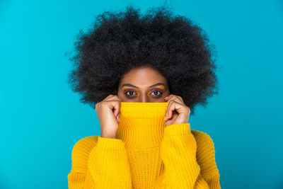 Portrait of woman covering face with t-shirt against blue background