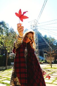 Low angle view of happy woman with autumn leaf on sunny day