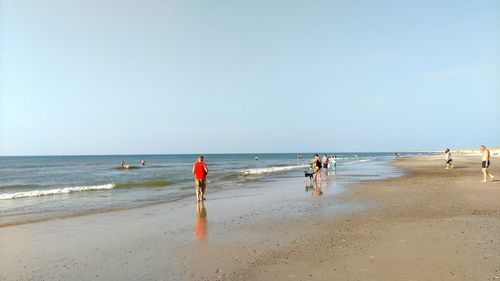 People on beach against clear sky