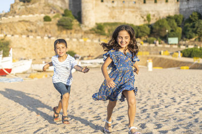 Girl running with brother at beach