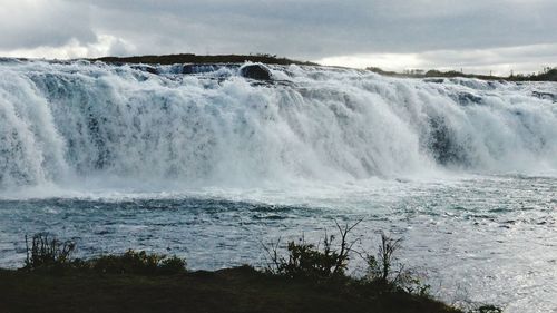 Scenic view of waterfall against sky