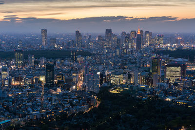Illuminated cityscape against sky during sunset