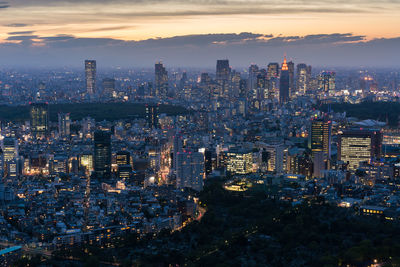 Illuminated cityscape against sky during sunset