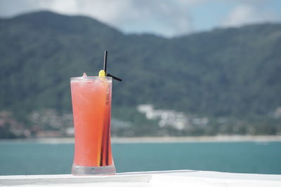 Close-up of cocktail on railing against mountain