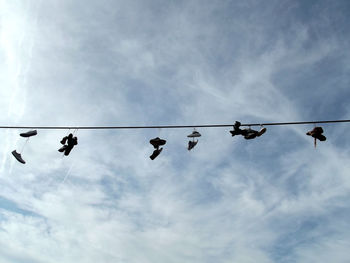 Low angle view of birds on cable against sky