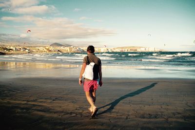 Full length of man walking on beach against sky