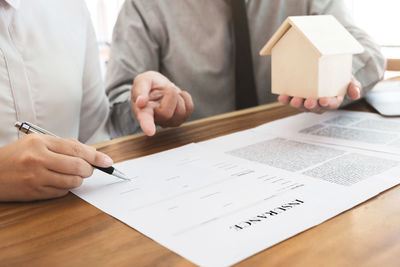 Midsection of man holding paper with text on table