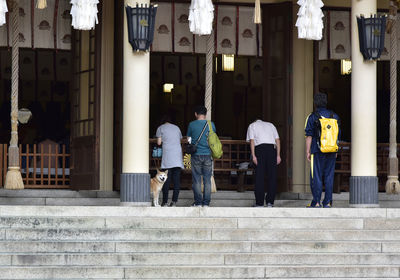 Rear view of people walking on steps in city