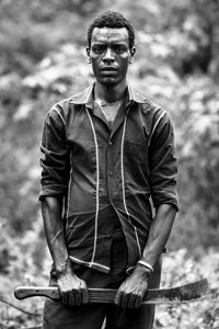 Portrait of young man standing with sword outdoors