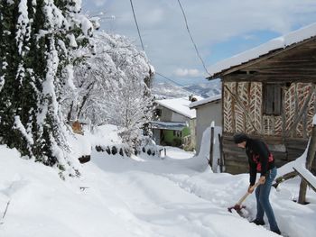 Man walking on snow covered houses against buildings