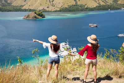 Full length of siblings standing on mountain against sea