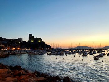 Boats moored at harbor during sunset