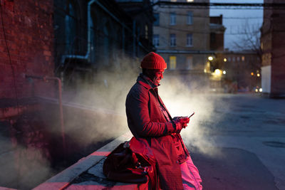 Smiling african man with smartphone on night street, black guy outdoors chatting in social media