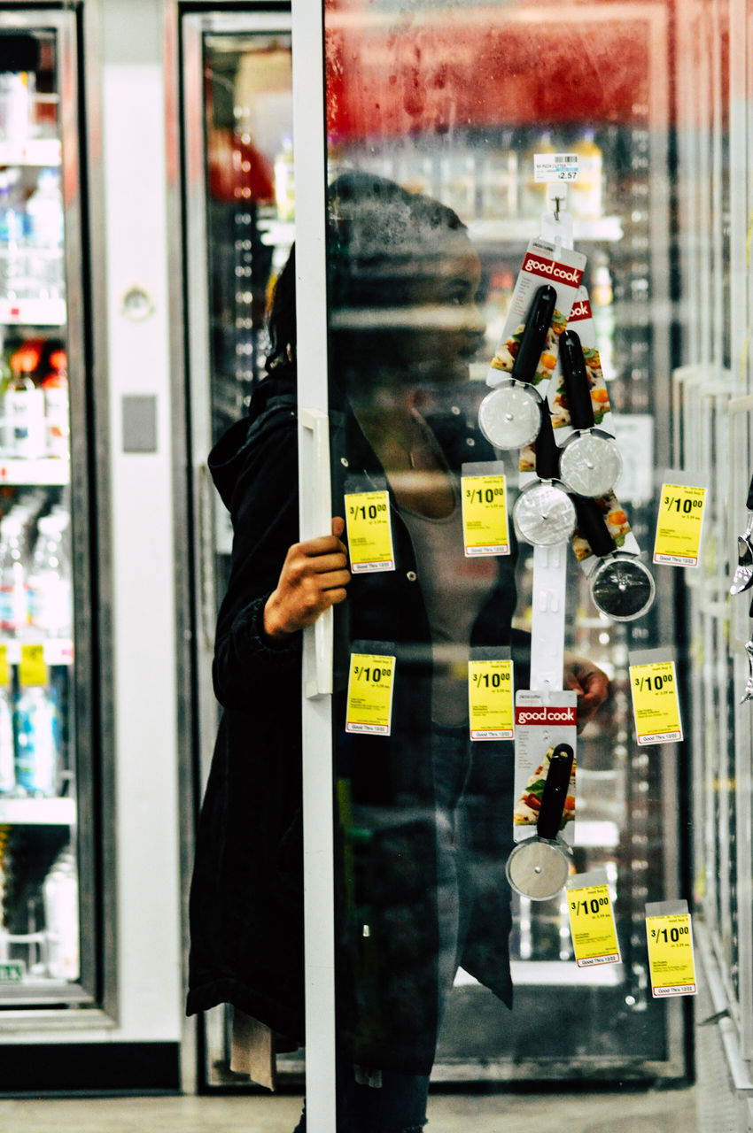 REFLECTION OF MAN ON GLASS WINDOW AT STORE