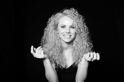 Portrait of smiling woman against black background