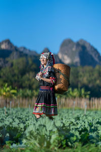 Woman holding umbrella on field by mountain against sky