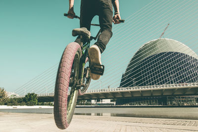 Low section of man riding bmx cycle on footpath in city