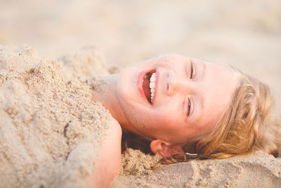 Portrait of happy girl buried in sand