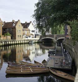 Boats moored on river by houses against buildings