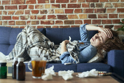 Portrait of woman using mobile phone while sitting against wall
