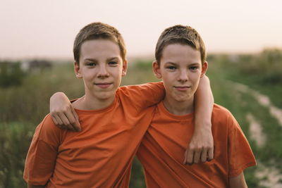 Funny twin brother boys playing outdoors on field at sunset.