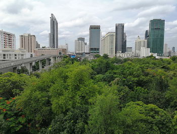 View of trees and buildings in city against sky