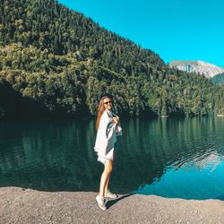 Full length of woman standing by lake against mountain