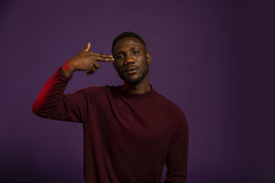 Portrait of young man standing against gray background