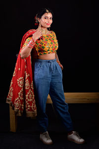 Portrait of woman standing against black background