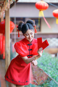 Woman holding red while standing against blurred background