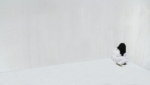 One woman hiding in the corner of an empty room