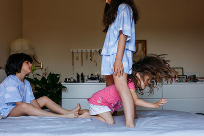 Three little girls with dark hair playing on parents bed