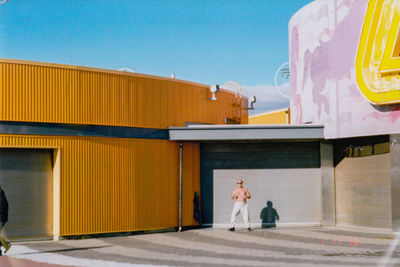 People walking in front of building against sky