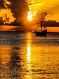 Silhouette sailboat in sea against sky during sunset