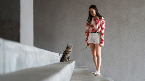 Full length of woman standing against wall