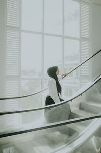 Side view of man with umbrella on staircase