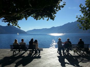 People sitting on table by sea against sky