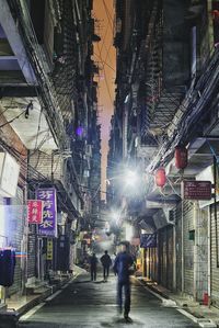 People walking on illuminated city street at night