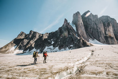 Rear view of people walking on mountain against sky