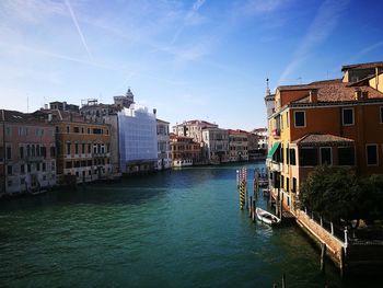 Canal amidst buildings in city against sky