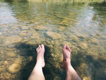 High angle view of man dangling legs over elbow river