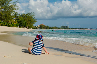 Rear view of man looking at beach against sky
