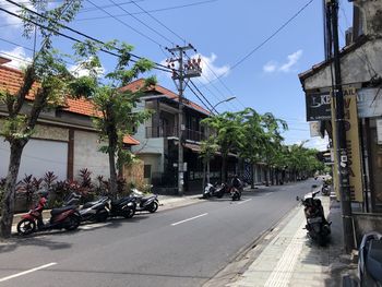 Cars on street by buildings in city against sky