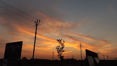 Low angle view of silhouette electricity pylon against sky during sunset