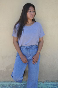 Portrait of a beautiful young woman standing against wall