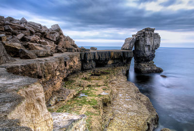 Rock formations by sea against sky